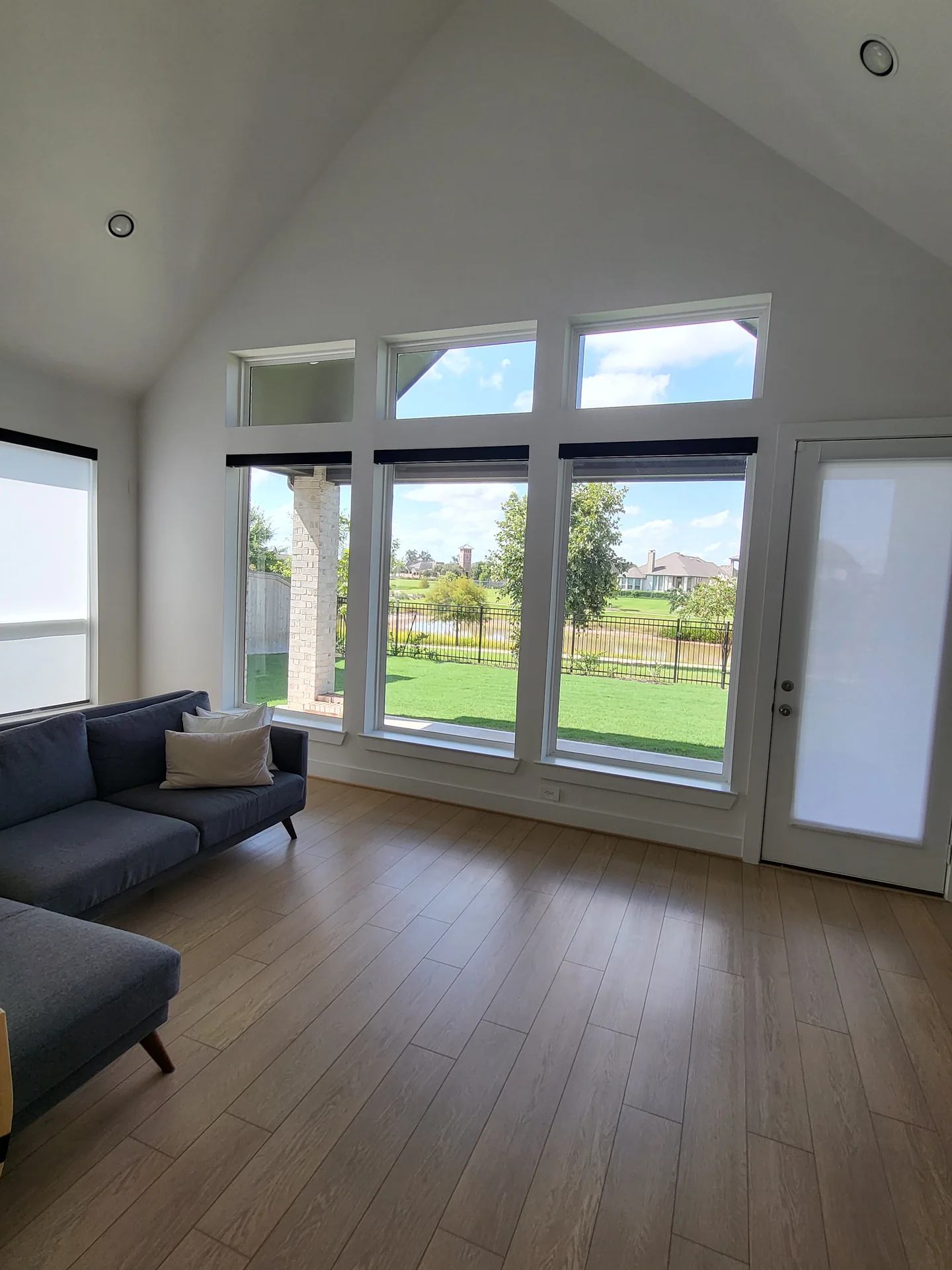 motorized roller shades lowered over floor-to-ceiling windows in a bright Houston living room